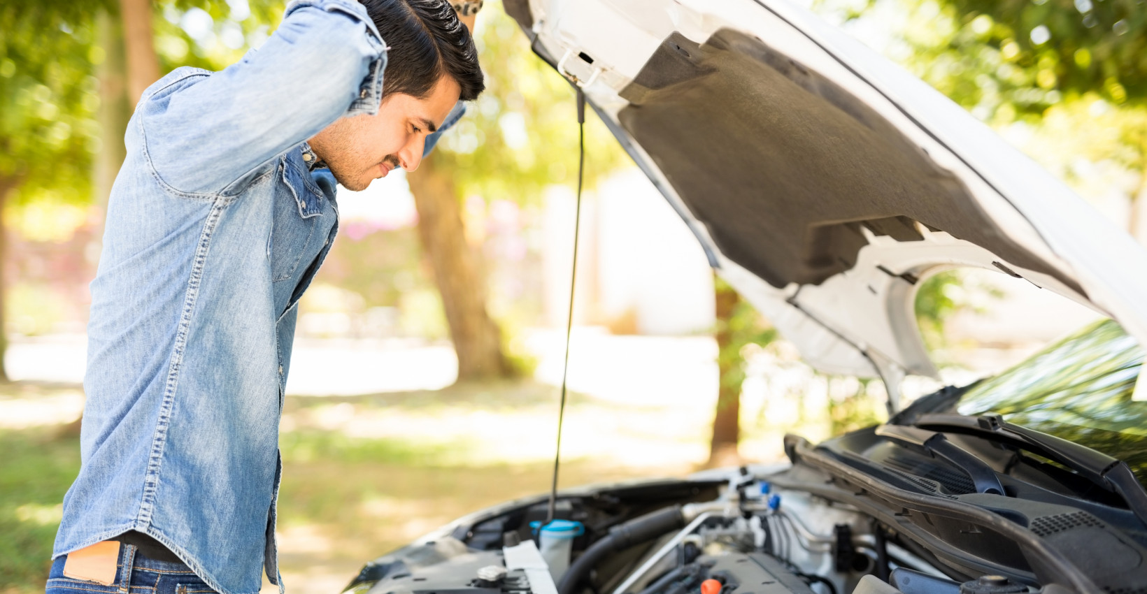 Person attempting to fix their car under the hood.