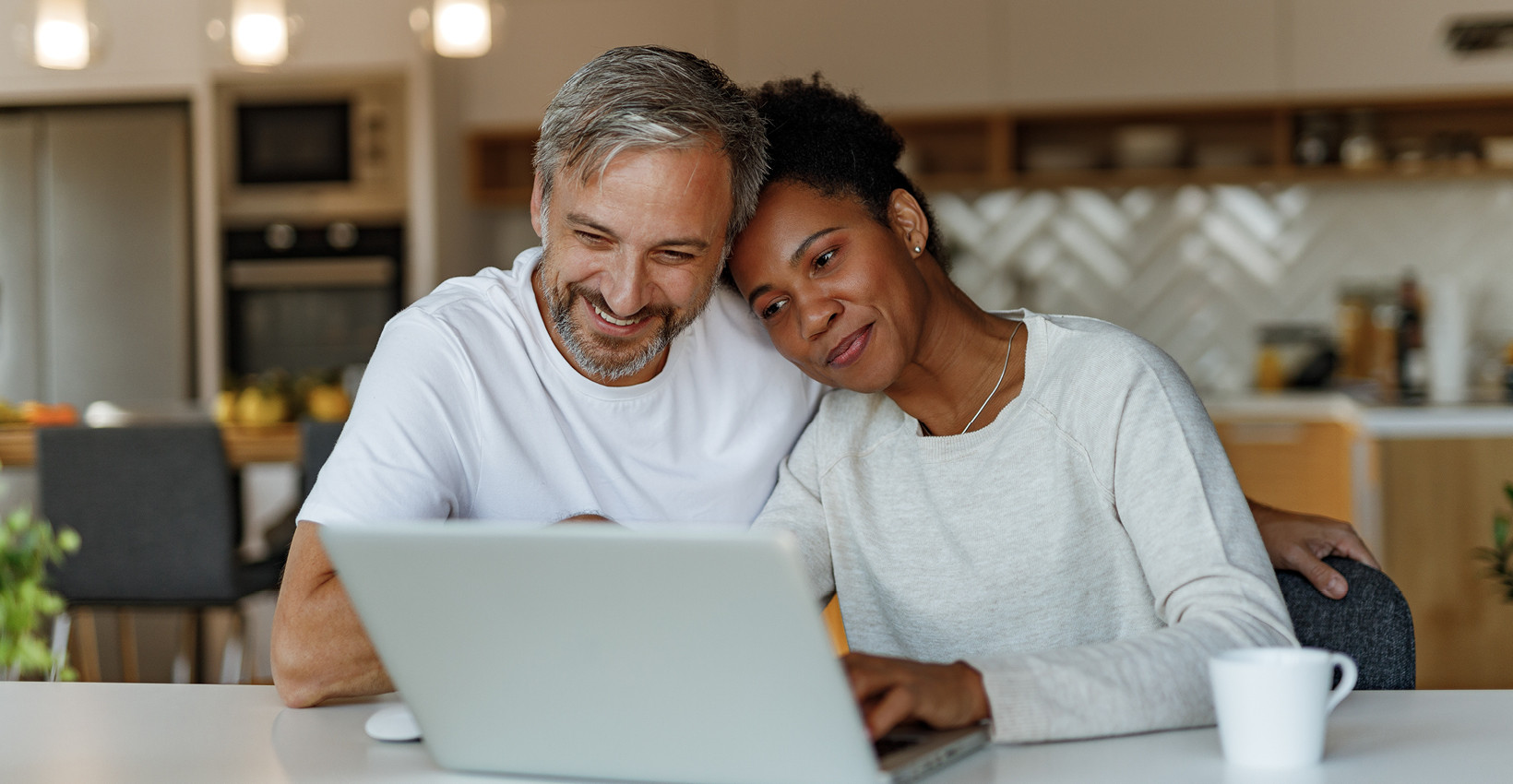 A husband and wife looking at a computer and cuddling for some reason. 