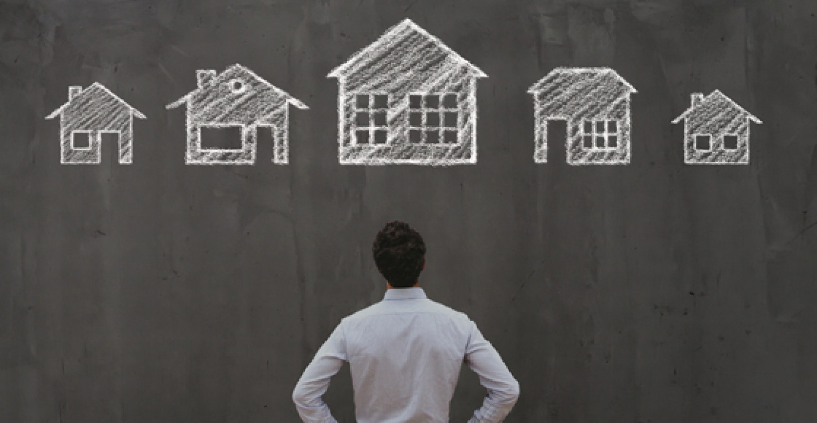 A man looking at a chalkboard with several houses drawn on it