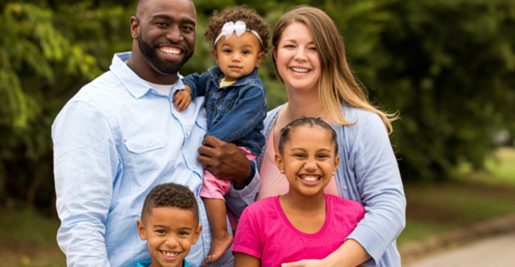 A husband, wife, and their three young kids posting for a family portrait