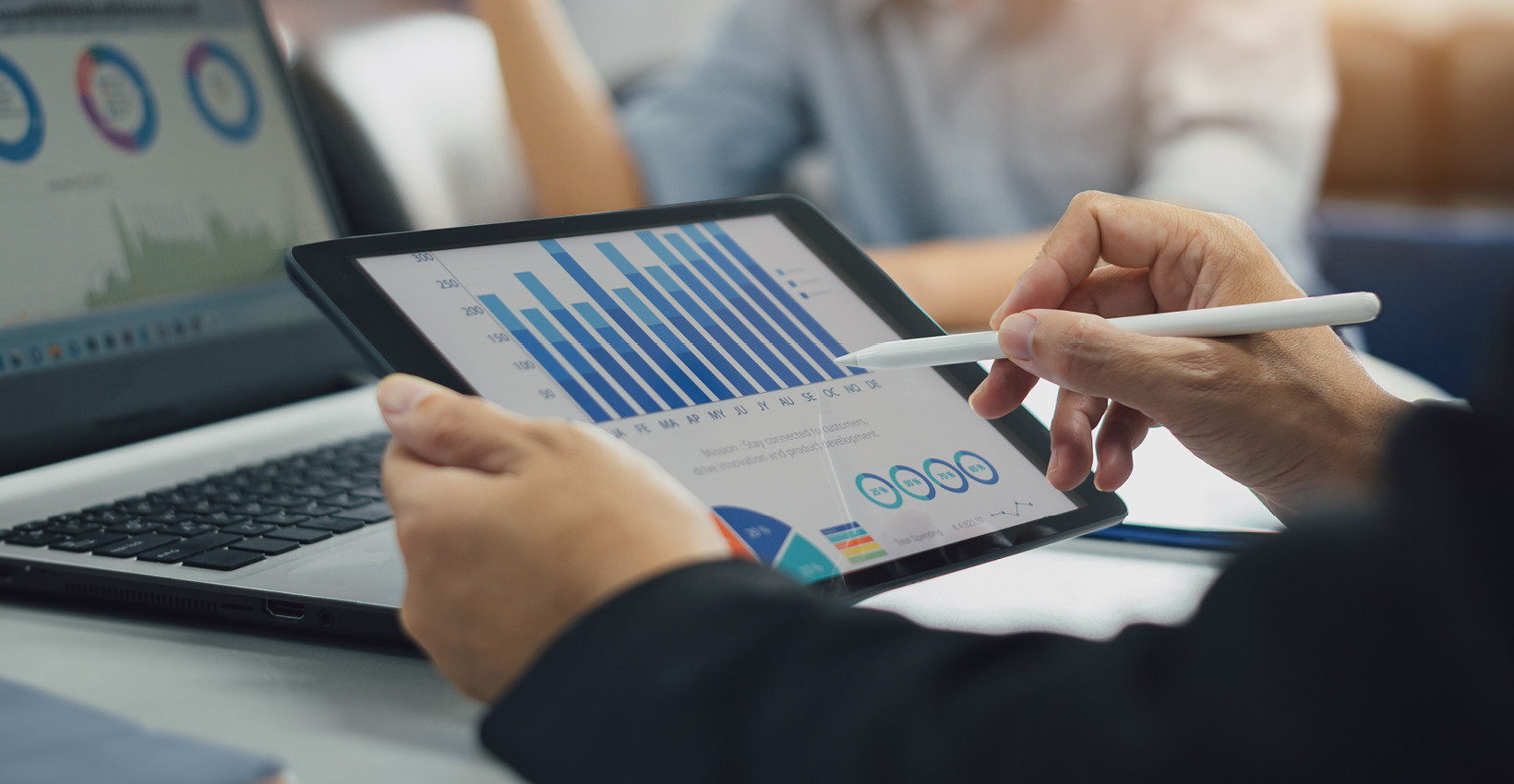 person holding a tablet looking at graphs