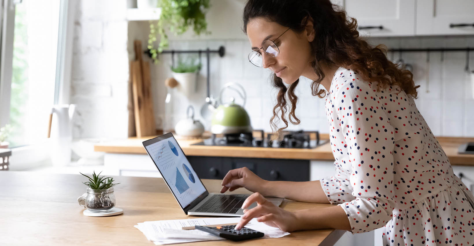 a woman with glasses looks at her laptop