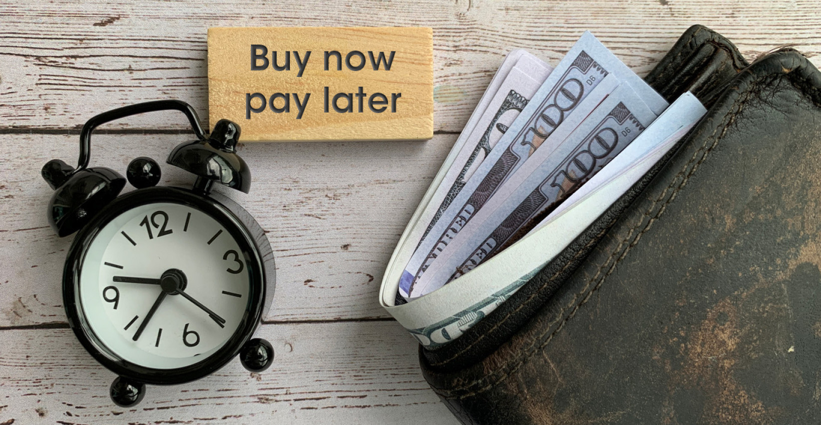 a wallet with money lays next to a clock