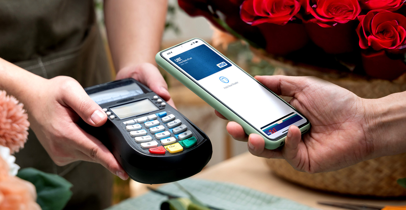 A person holds their phone near a card reader to pay with mobile wallet