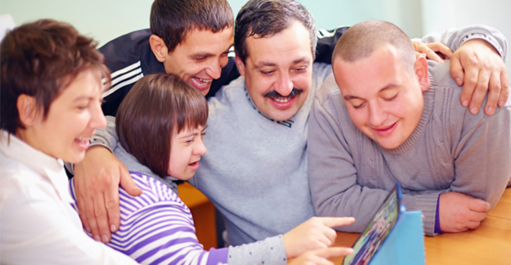 a group of people gather around a tablet