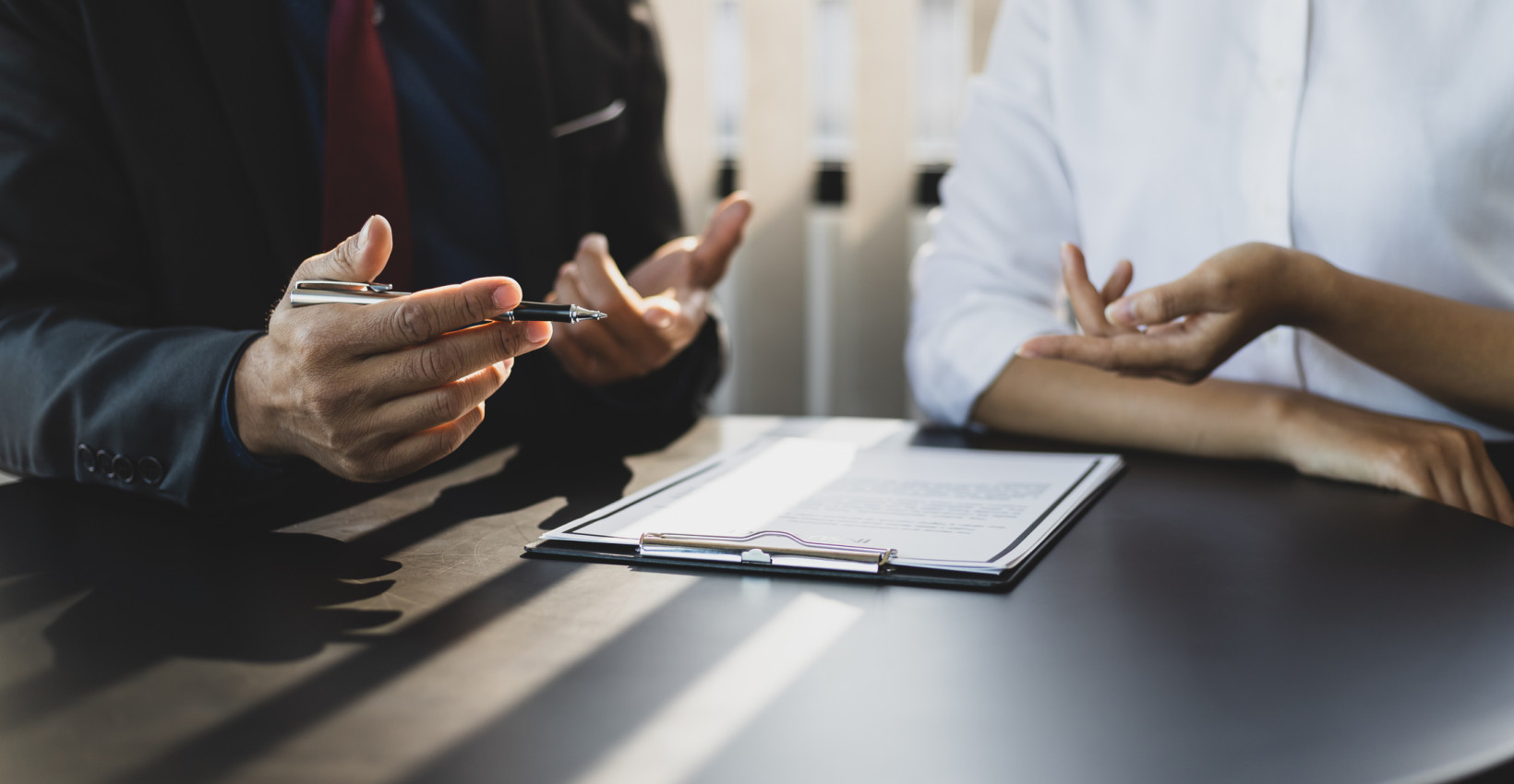 two people sit at a desk with paper between them