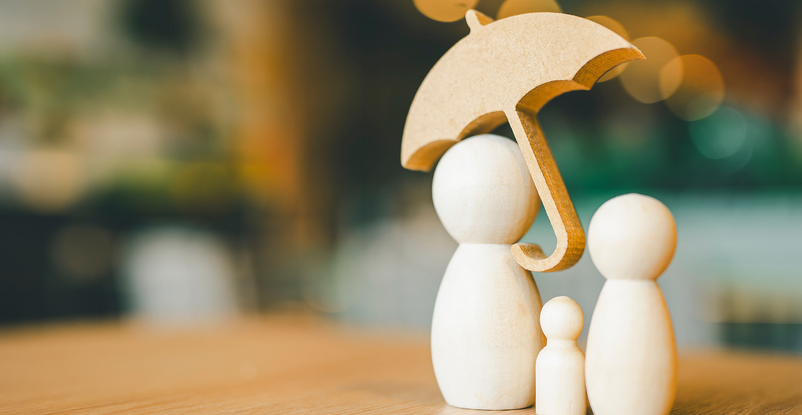 2 big and 1small wooden figure stand under a wooden umbrella