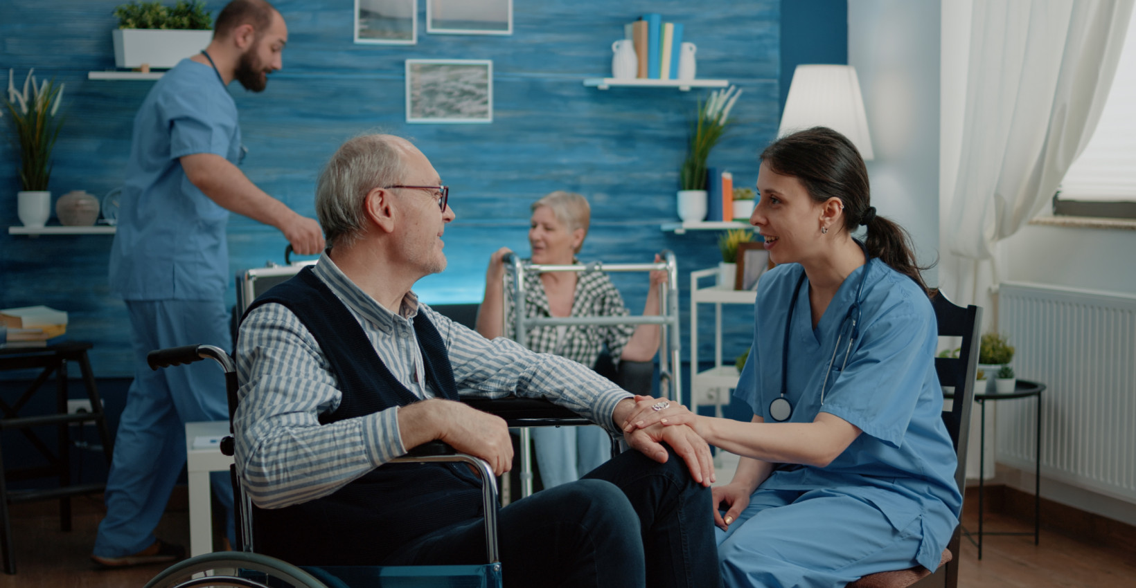 an elderly patient sits with a male and female nurse in a home