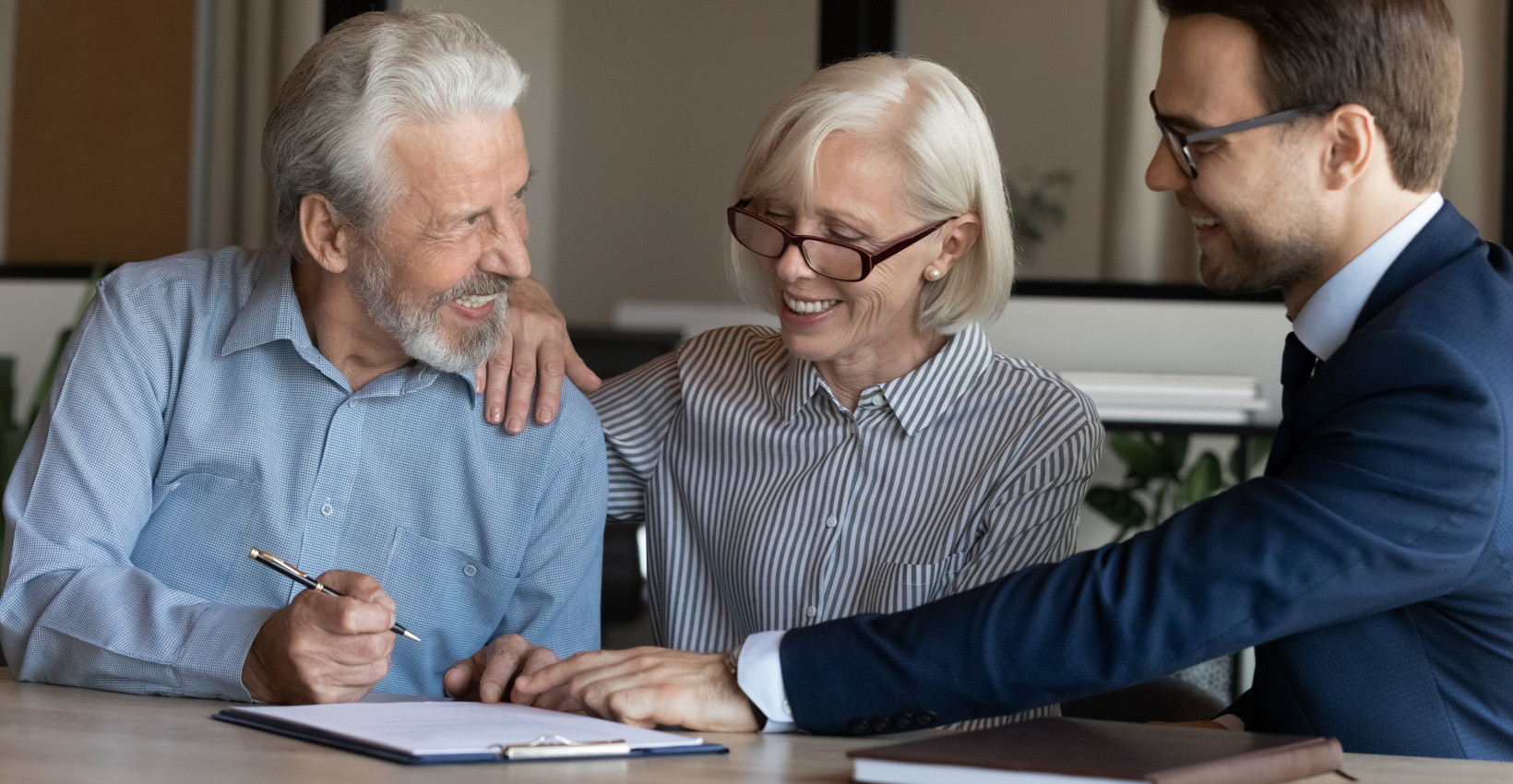 an older couple sit with a younger man filling out paperwork