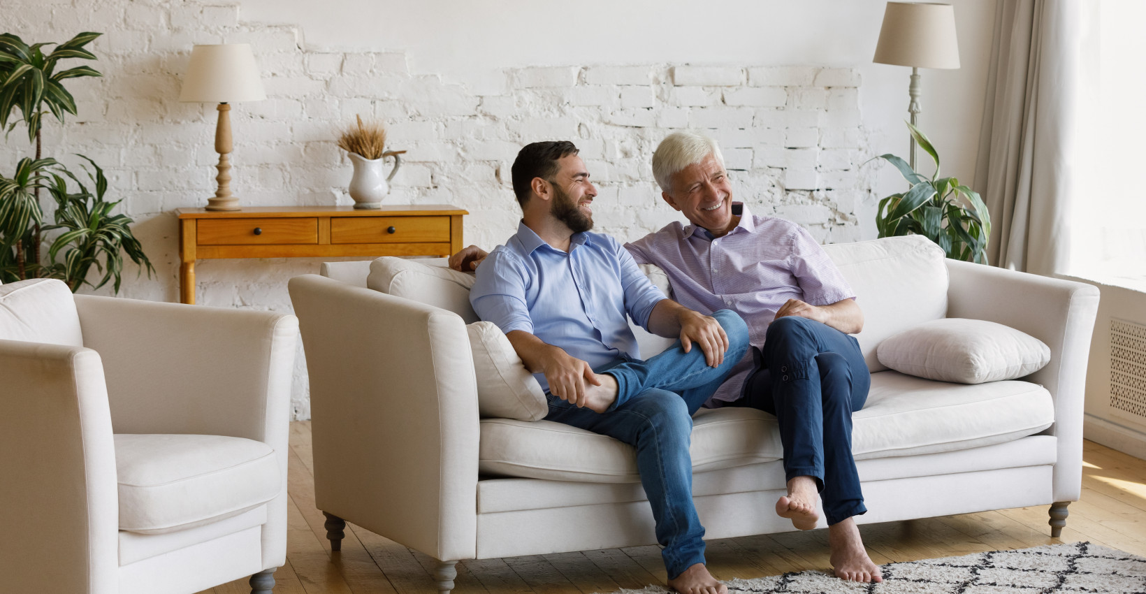 a young man sits with an older man on a couch