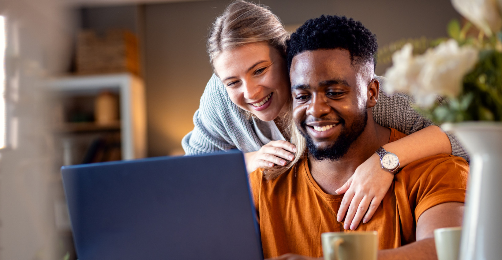 a happy couple look at a laptop screen together