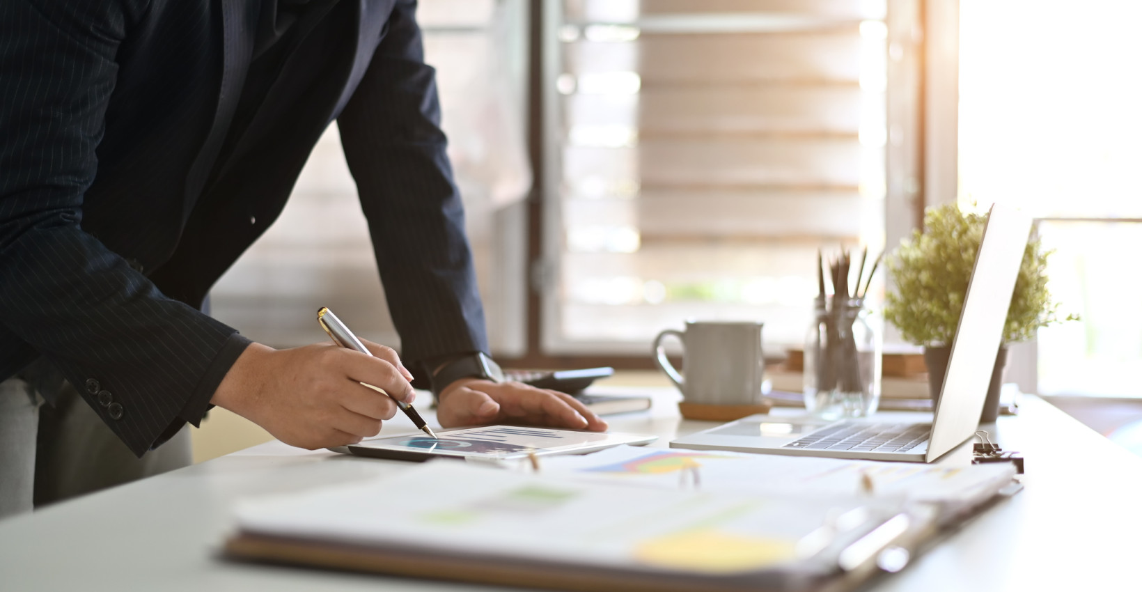 a person stands at a desk writing