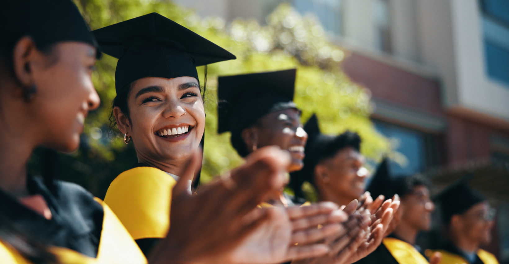 a group of graduates sit together clapping