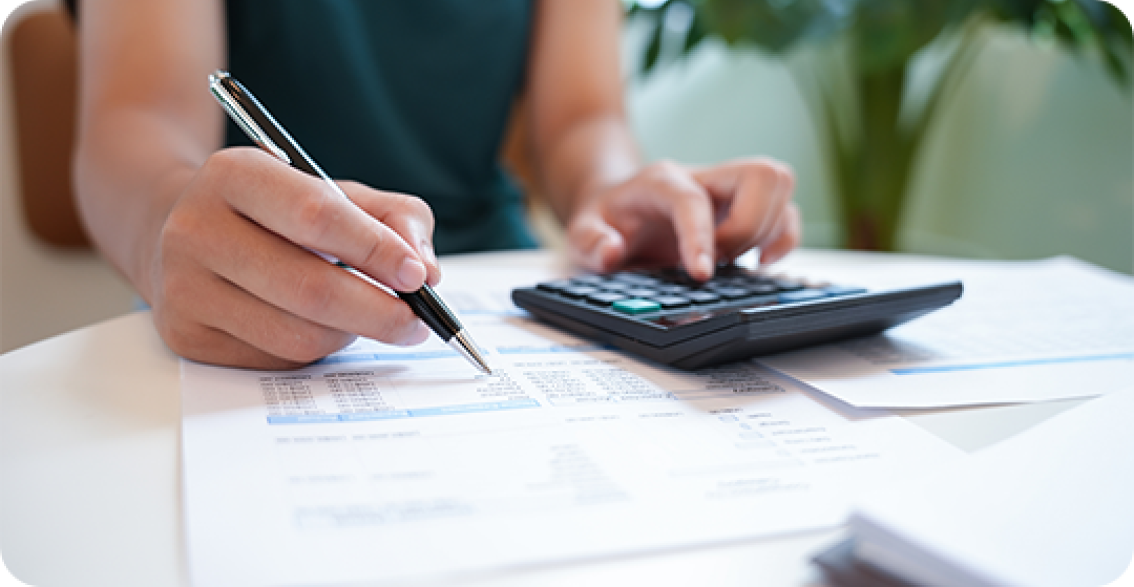 a woman writes on a paper with a calculator near by