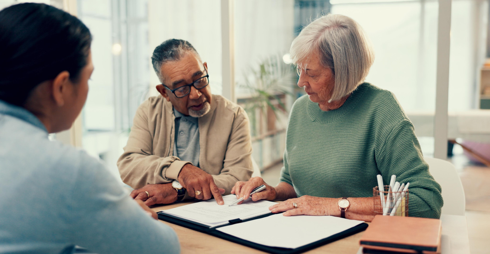 an older man and woman sit at a table review documents with another man