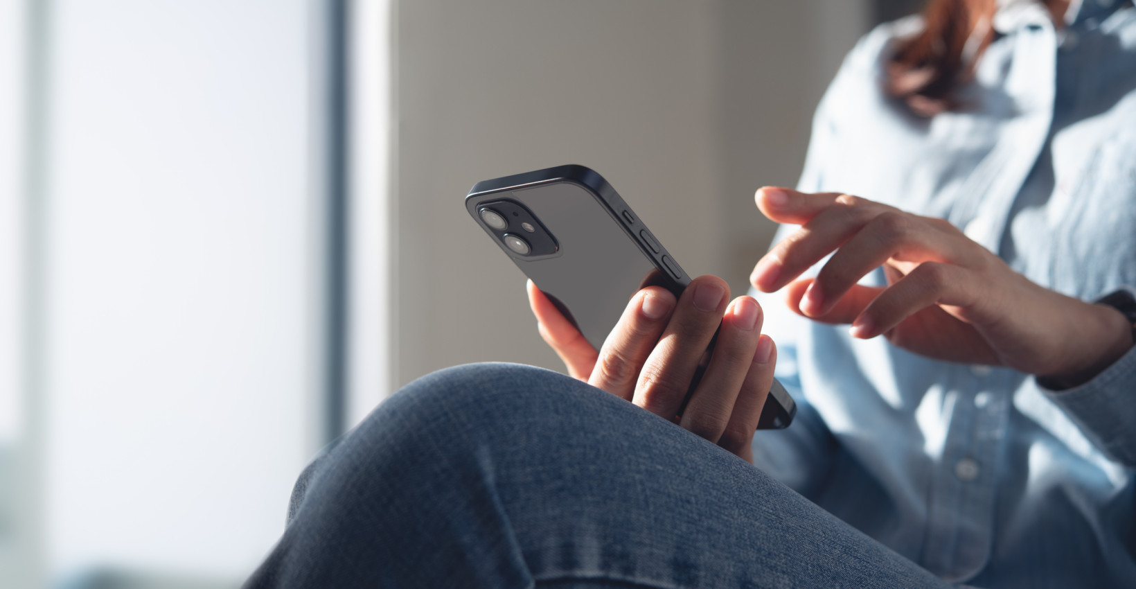 A woman holding her phone and tapping it