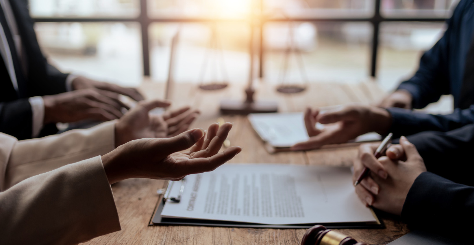 four people sit at a table with their hands visable