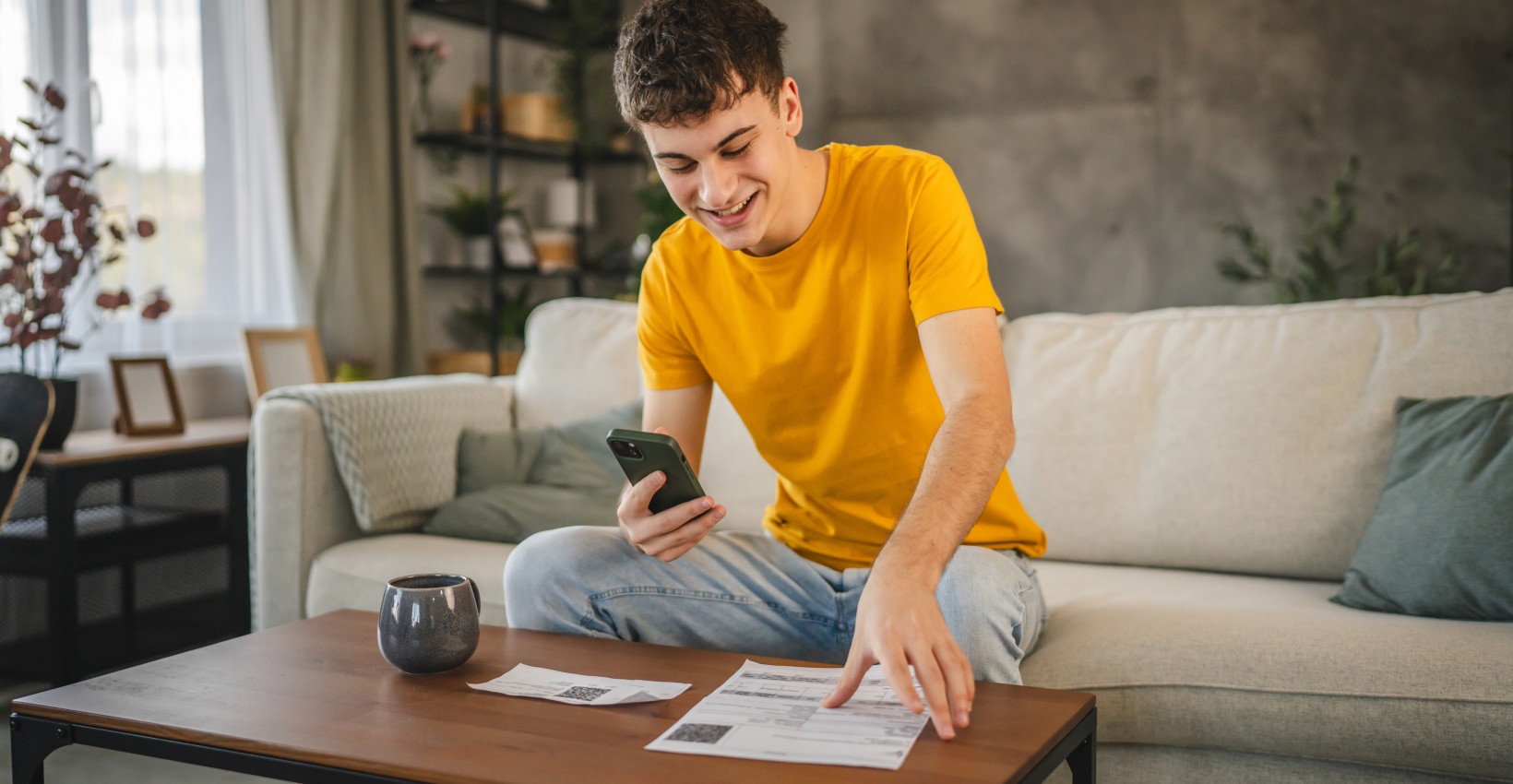 A young boy sitting on the couch and looking at his phone
