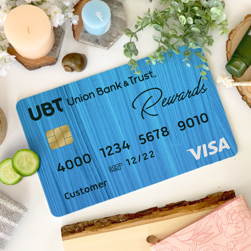 A UBT credit card on a table surrounded by spa items, like candles, plants, and cucumber slices