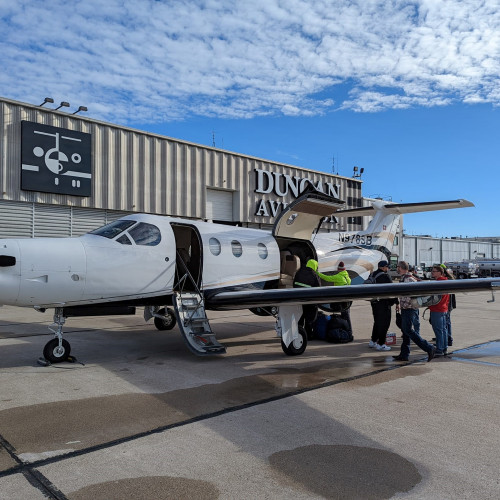A group boarding a small plane outside of Duncan Aviation.