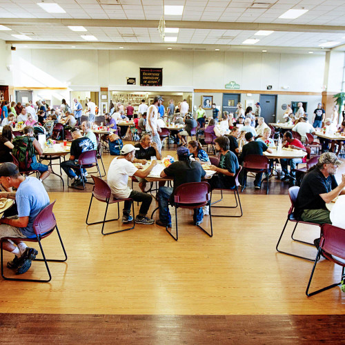 A group of people eating in a homeless shelter