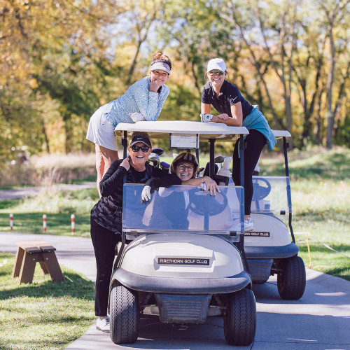 Fundraiser attendees pose on a golf cart.