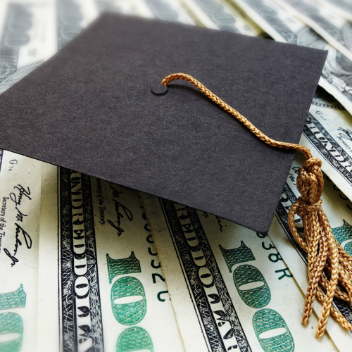 A cap and tassel on a bunch of hundred dollar bills