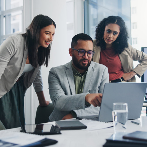 Three people looking and pointing at a laptop