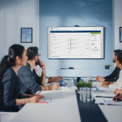 A group of people looking at a big screen in a conference room