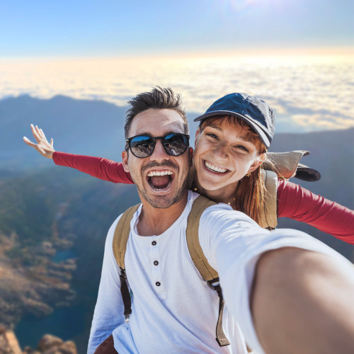 a man and a woman stand at the top of a mountain smiling