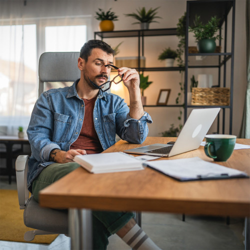 man sits at his desk with his laptop