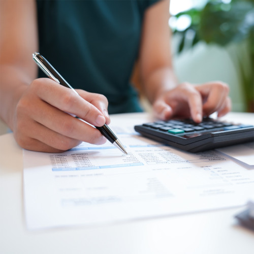 woman rights on paper with a calculator near by