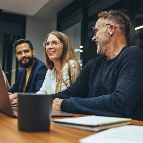 Three people sit at a table laughing 