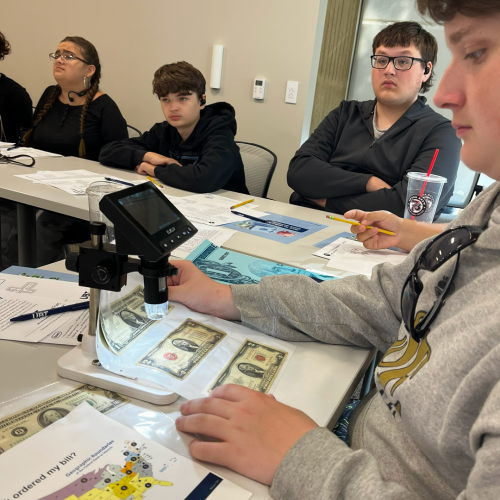 students look at money under a microscope