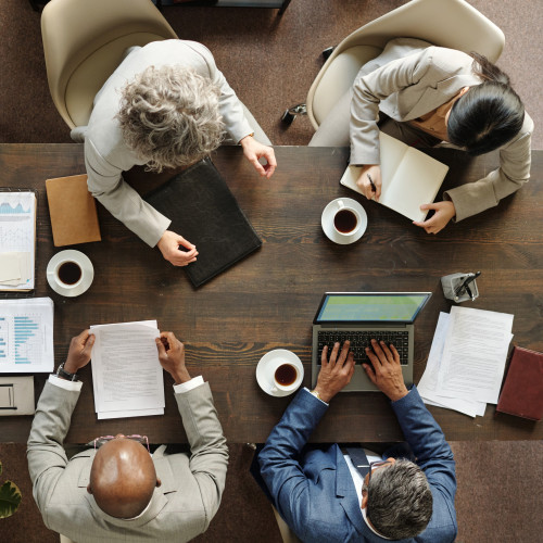 A group of 4 people having a meeting at a wooden table. 
