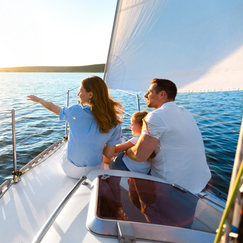 a mom, dad, and child sit on a sail boat on the water