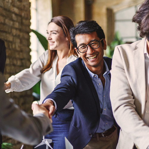 A man smiling as he reaches out to shake another man's hand