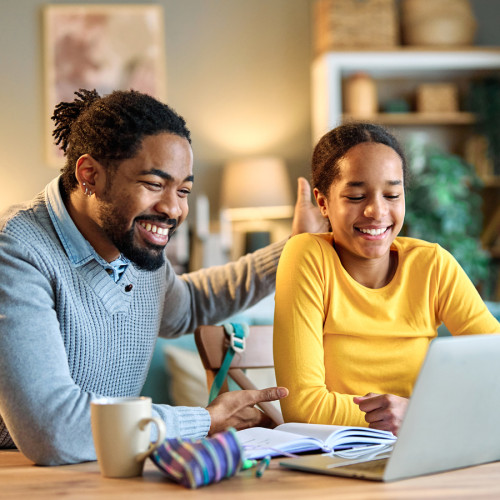 A father and his daughter smile while they look at a computer