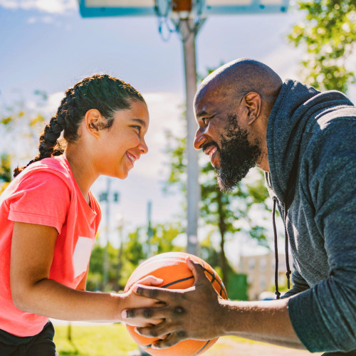 a dad and daughter play basketball