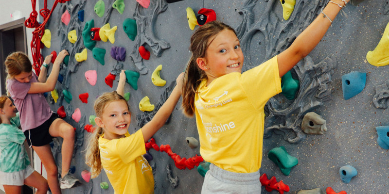 two young children enjoy the rock climbing wall at camp sonshine