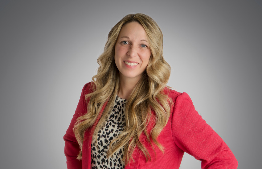 A headshot of April Lewis wearing a red blazer
