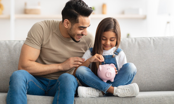 A father and daughter putting a coin in a piggy bank