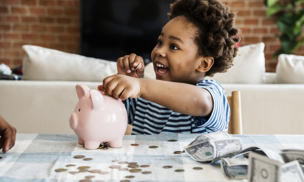 Young boy putting a coin in a piggy bank