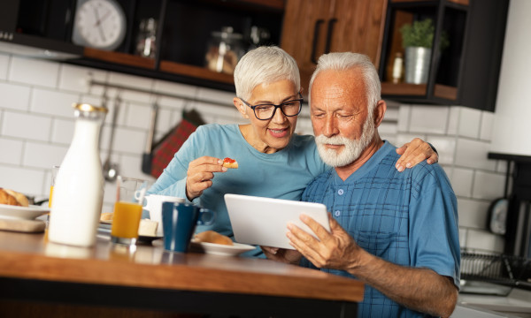 An elderly couple looking at a piece of mail at the kitchen table