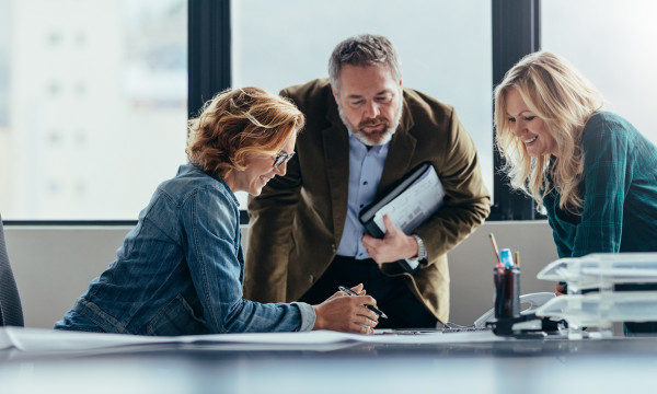 A group of people crowding around a laptop