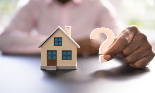 tiny house next to a man holding a question mark