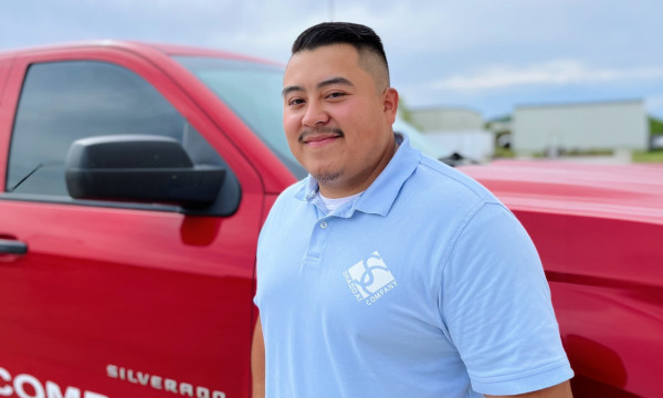 Luis Hong stands in front of his red truck