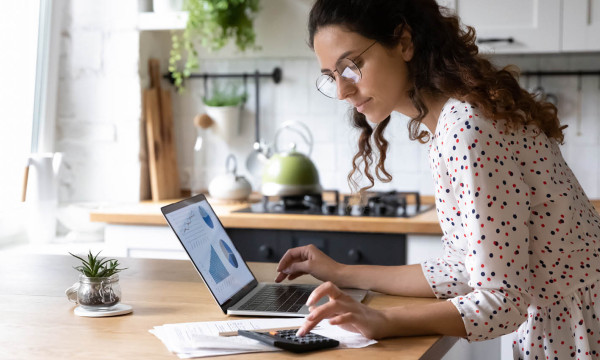 a woman with glasses looks at her laptop
