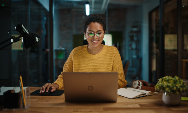 a woman sits at a table with her laptop