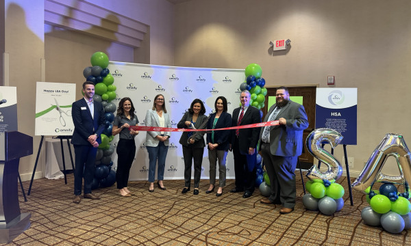 omnify employees stand in front of a ribbon to cut